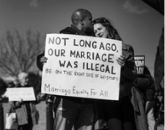 A couple holding a banner saying 'Not long ago our marriage was illegal'