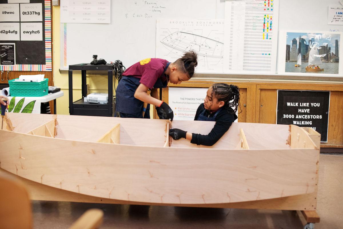 Photo of two young people building a small boat